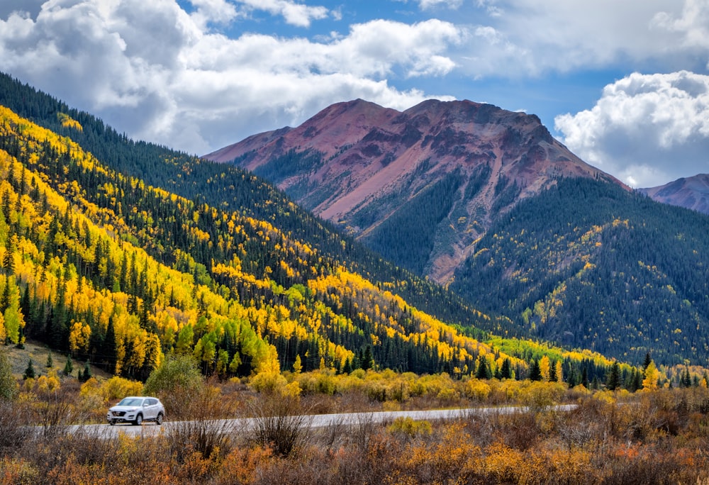 a car driving on a road in front of a mountain