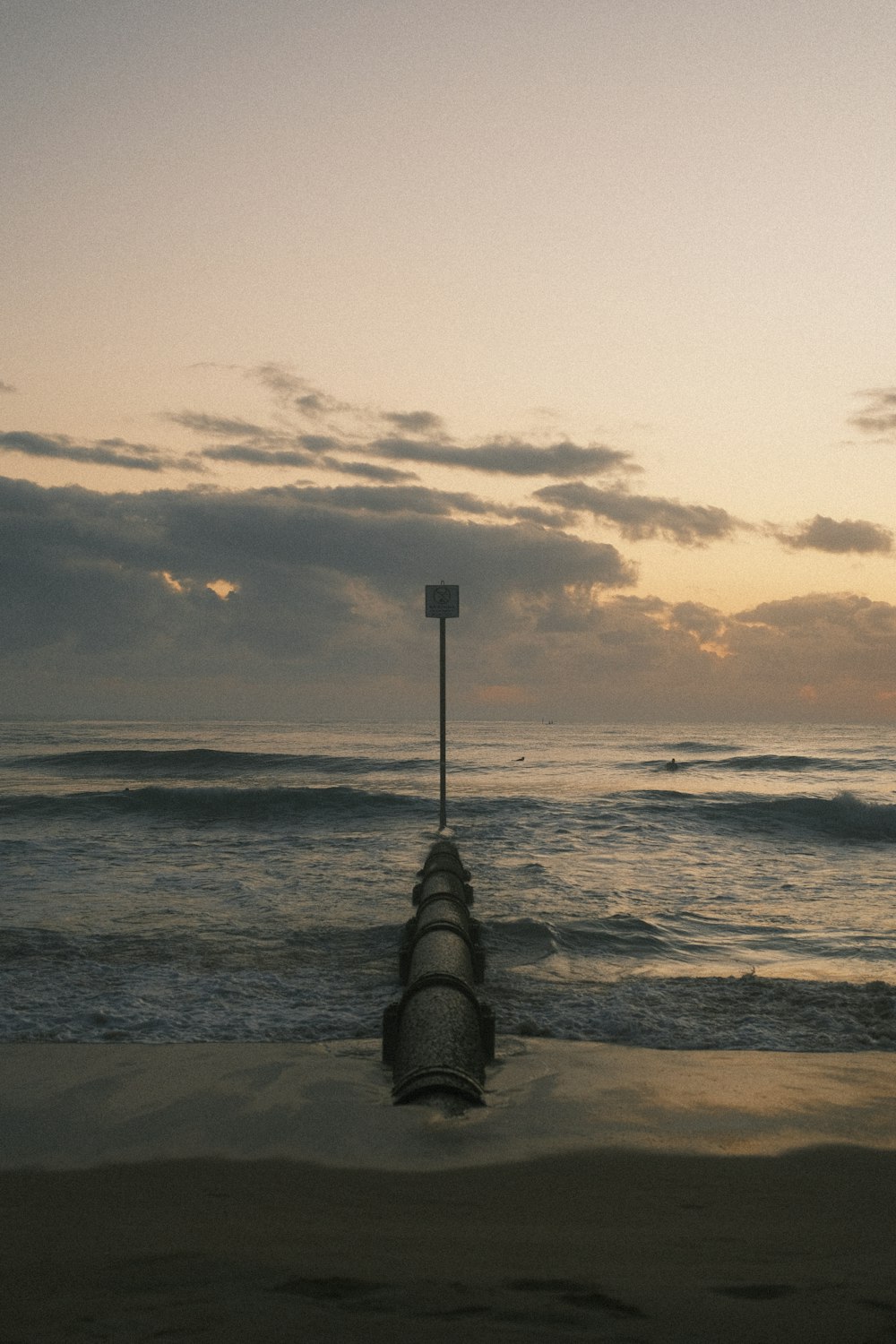 a beach with a sign and a pole in the water