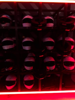 Array of tactical helmets lined up on a metal rack under soft lighting.