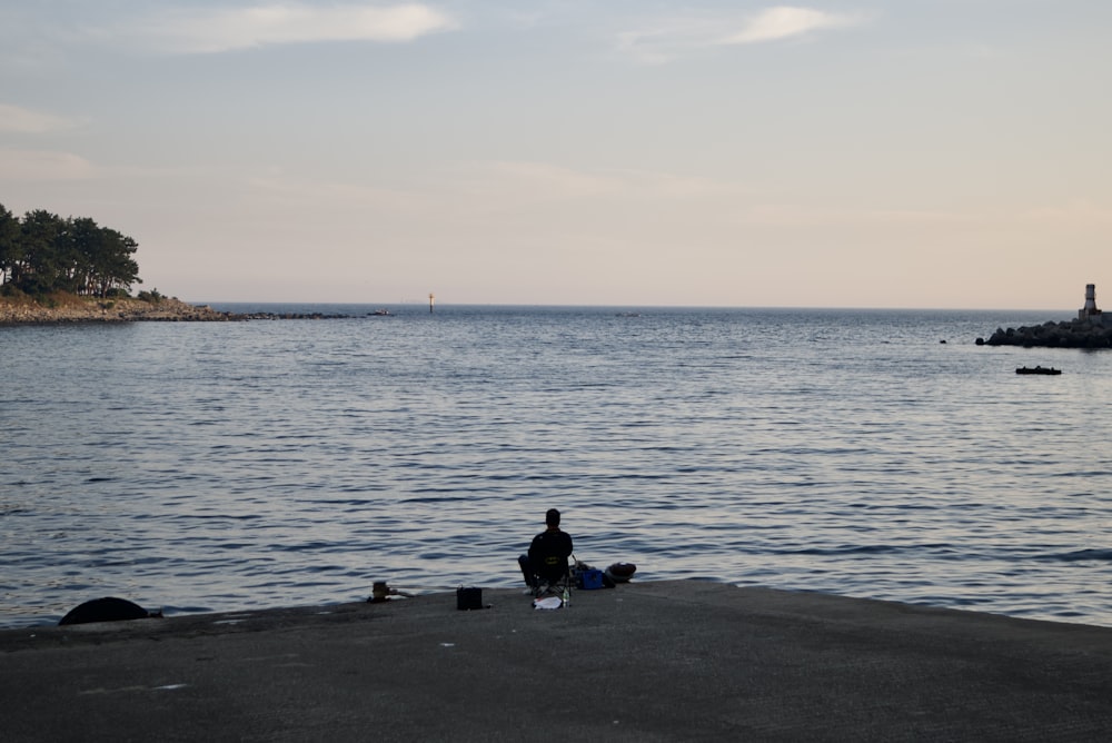 a person sitting on a chair by the water