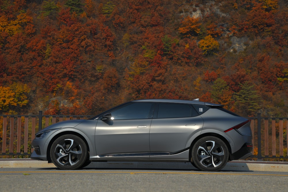 a silver car parked on the side of a road with trees in the background