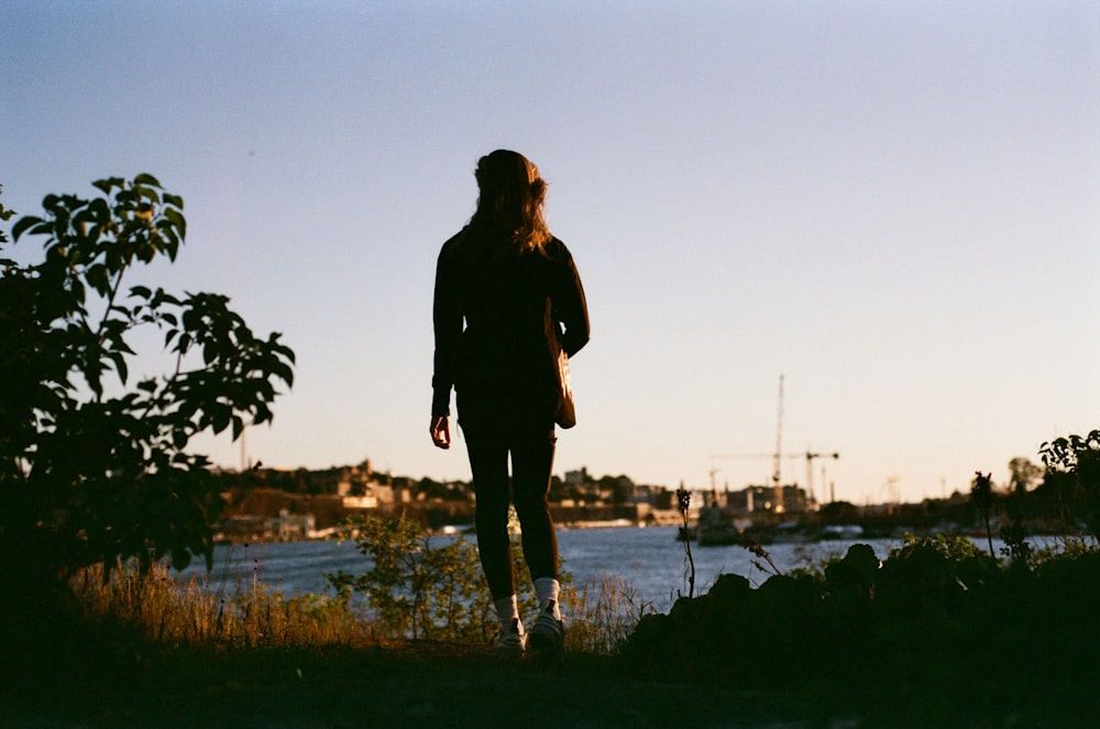 a person standing on grass by a body of water