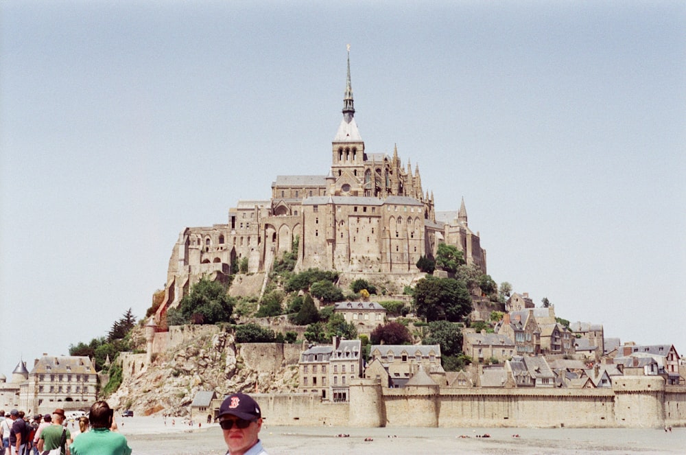 un castillo en una colina con el Mont Saint-Michel al fondo