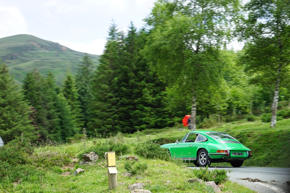 a car parked on a hill with trees and mountains in the background