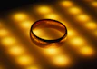 A luxurious gold ring with intricate patterns glowing softly under warm lighting
