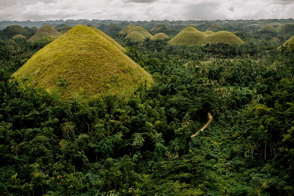 a group of green hills with Chocolate Hills in the background
