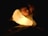 A child peacefully sleeps, holding a glowing night light that resembles a smiling face. The light casts a warm glow, illuminating the child's face and surrounding area in the darkness.