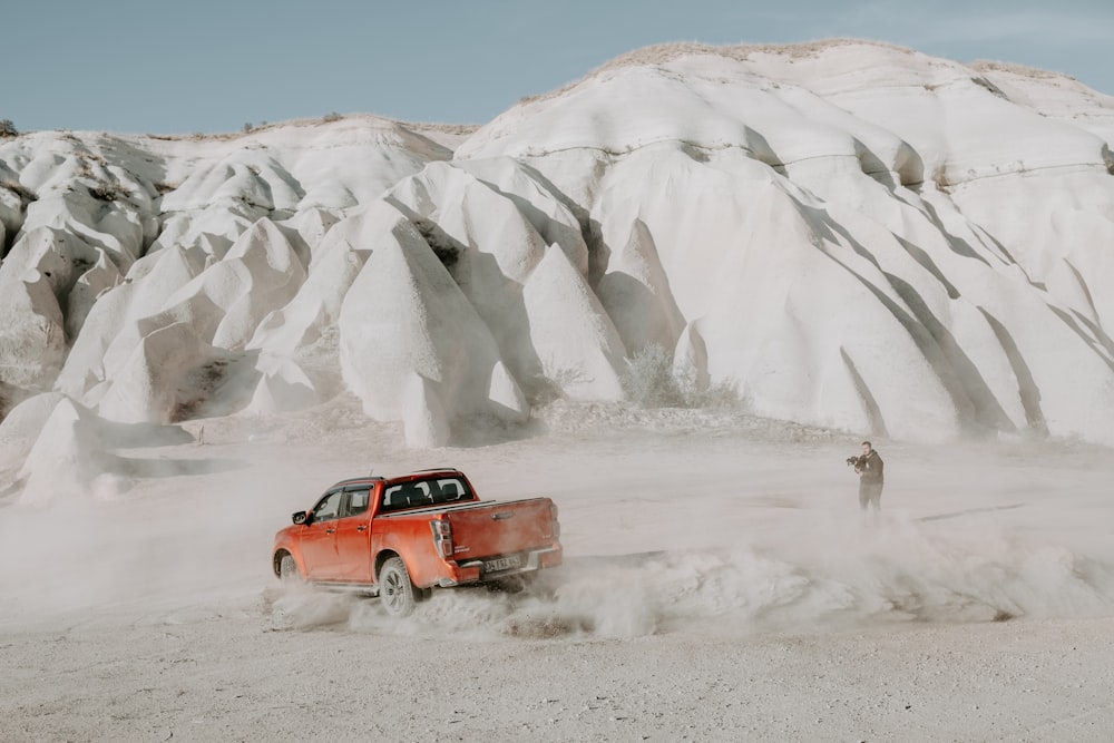 a red truck driving through snow