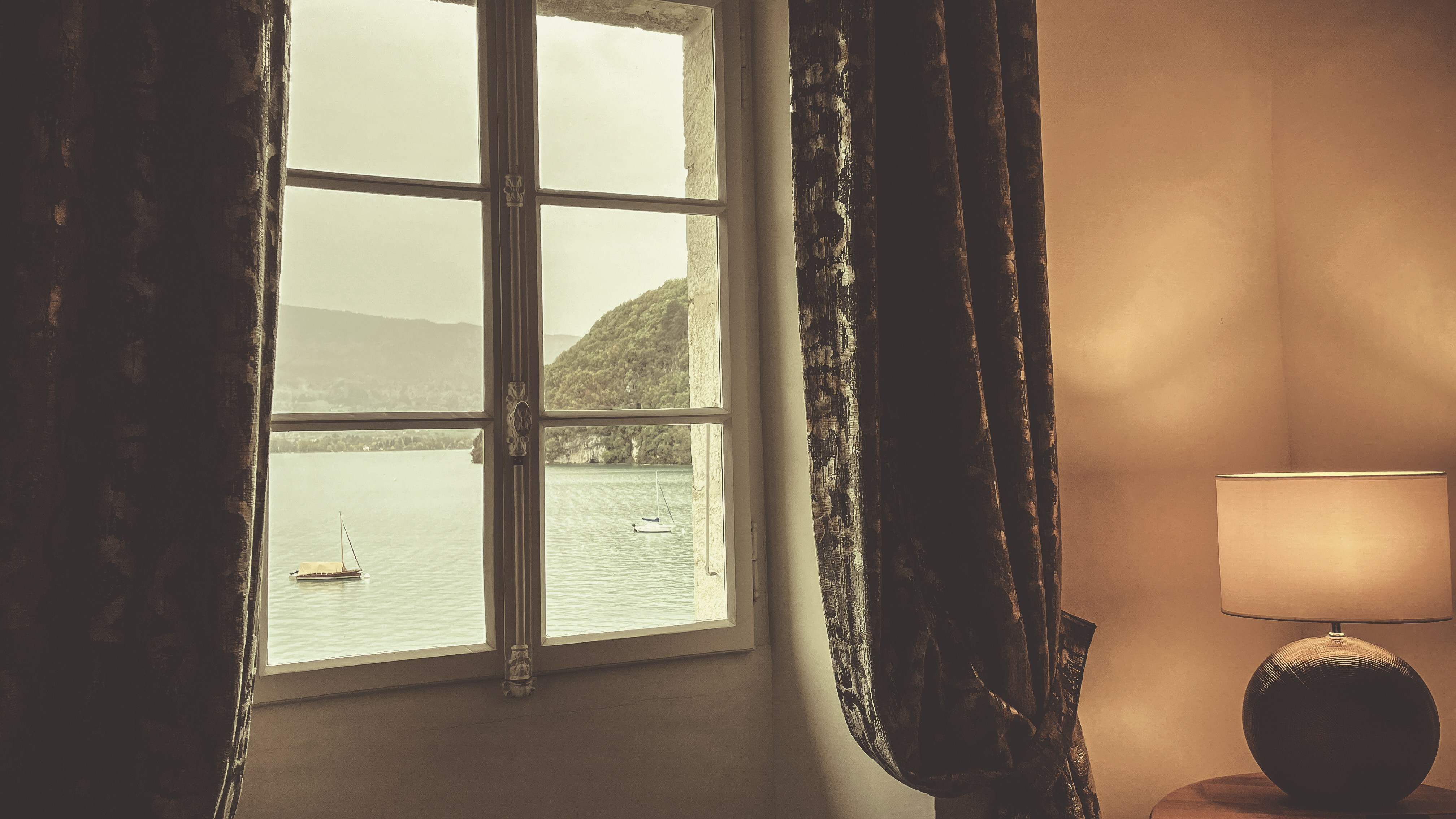 a window with a view of a lake and a boat