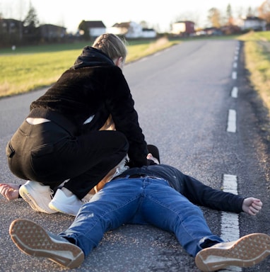 a man kneeling on the side of a road with another man kneeling on the ground