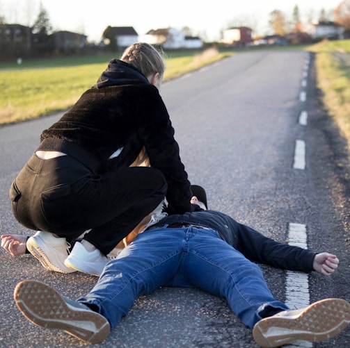 a man kneeling on the side of a road with another man kneeling on the ground