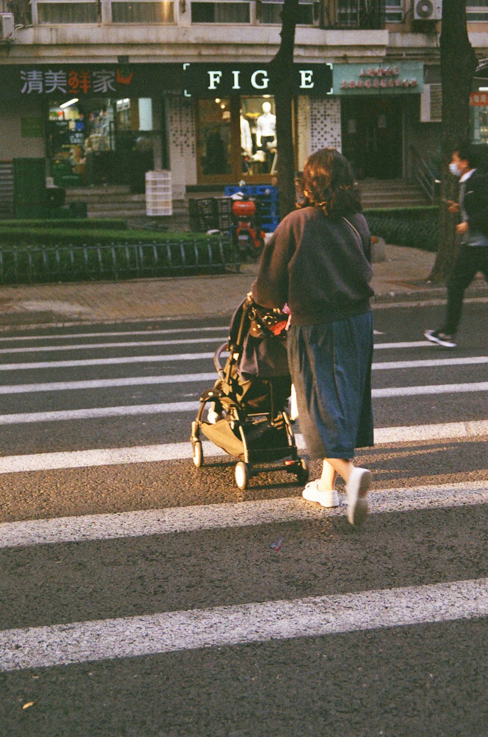 a person walking a stroller across a crosswalk