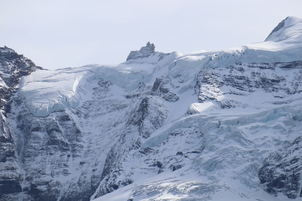 uma montanha nevada com um edifício no topo