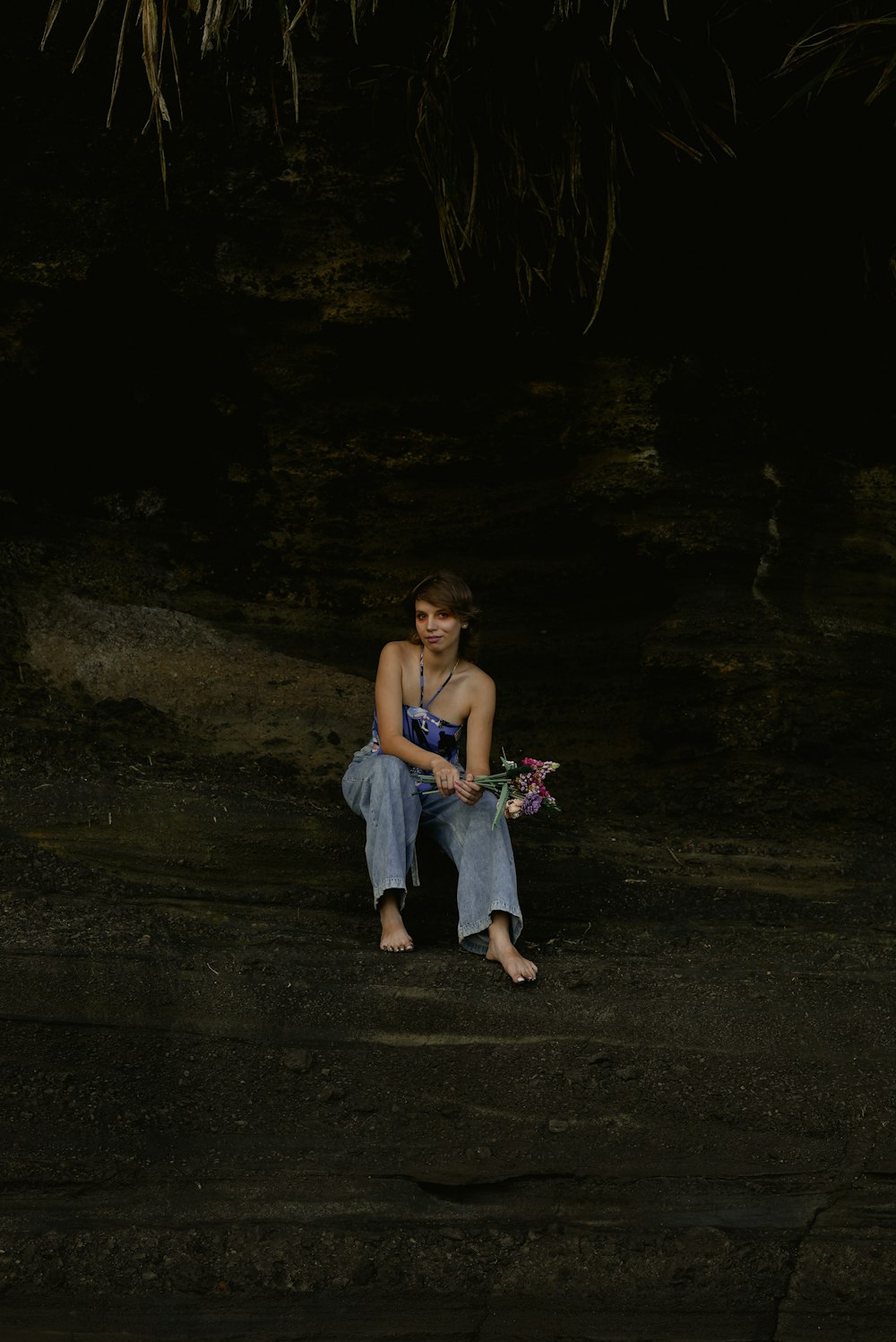 a person sitting on a wood floor holding flowers
