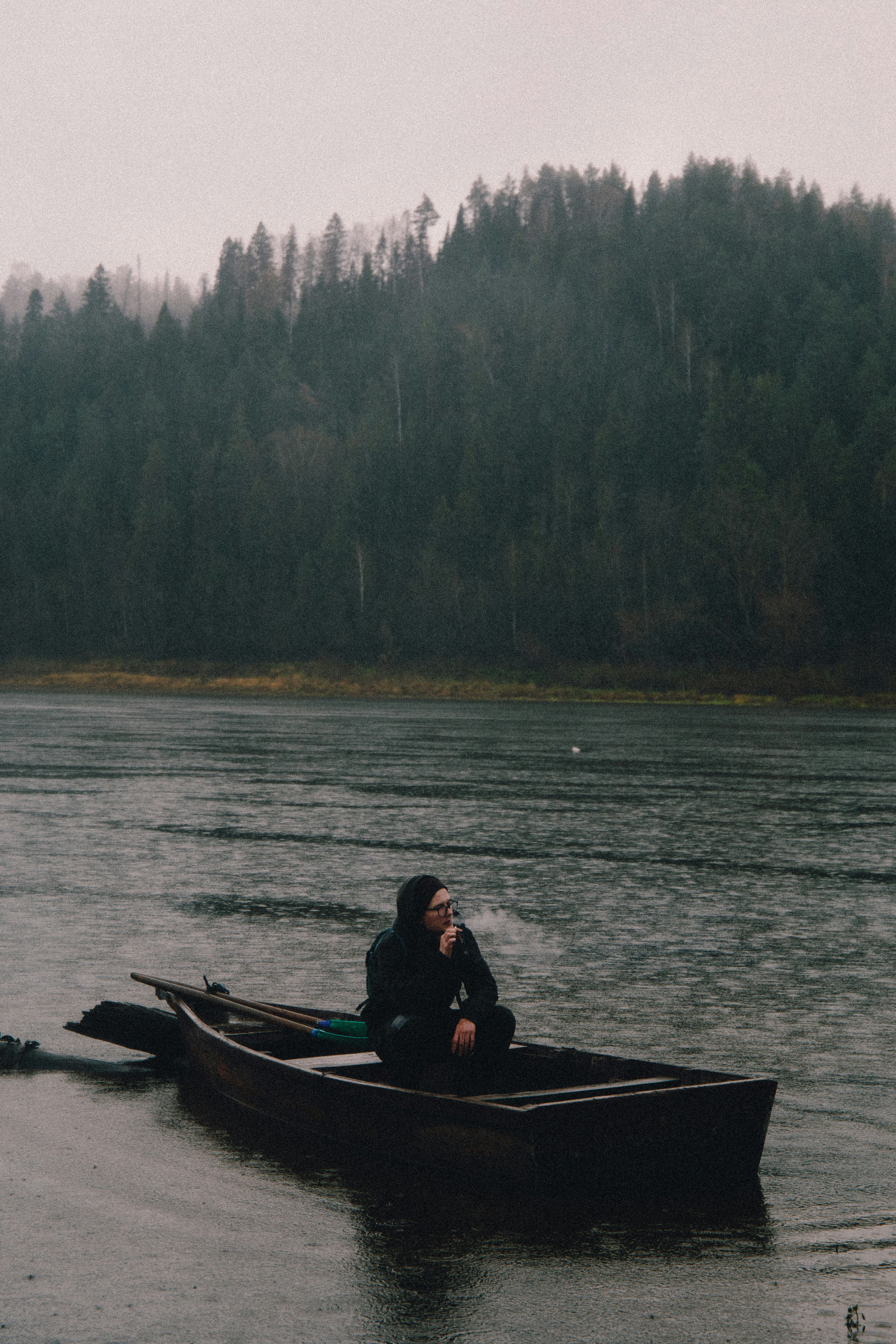 a man in a canoe on a lake with trees in the background