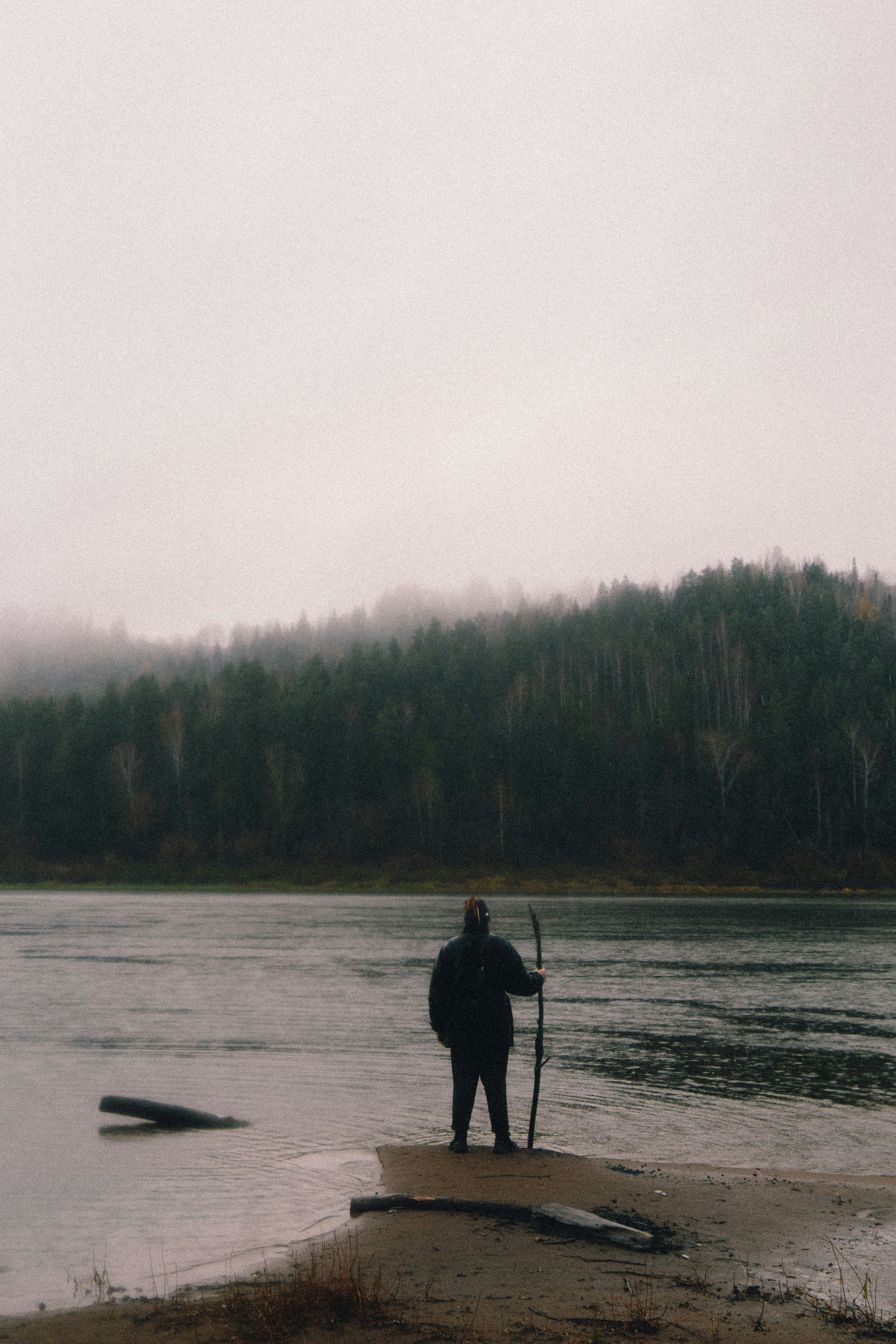 a person standing on a beach holding a stick