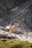 Aerial shot of a large stone quarry with excavators and trucks working amid rocky terrain.