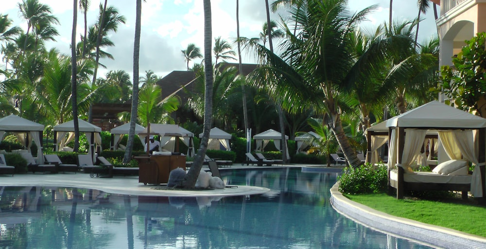 a pool with lounge chairs and umbrellas by a building