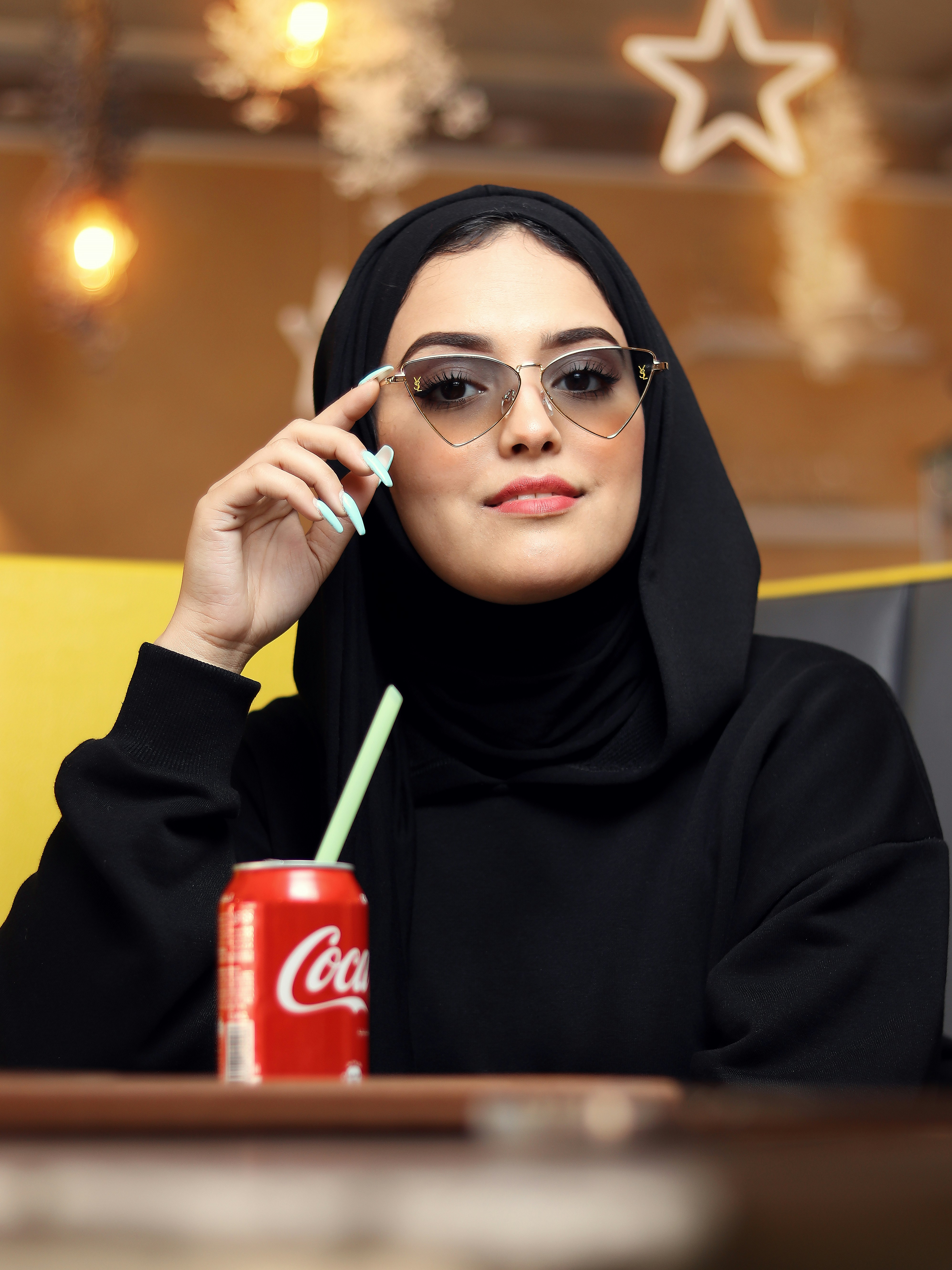 Seorang wanita mengenakan jilbab hitam dan memegang rokok