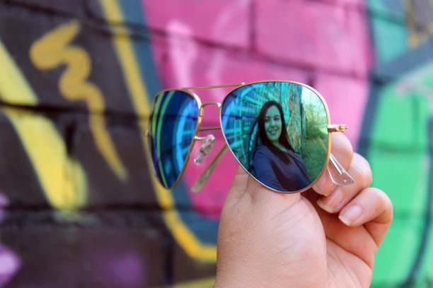 A cheerful customer wearing vivaaura sunglasses, smiling against a backdrop of vivid street art.