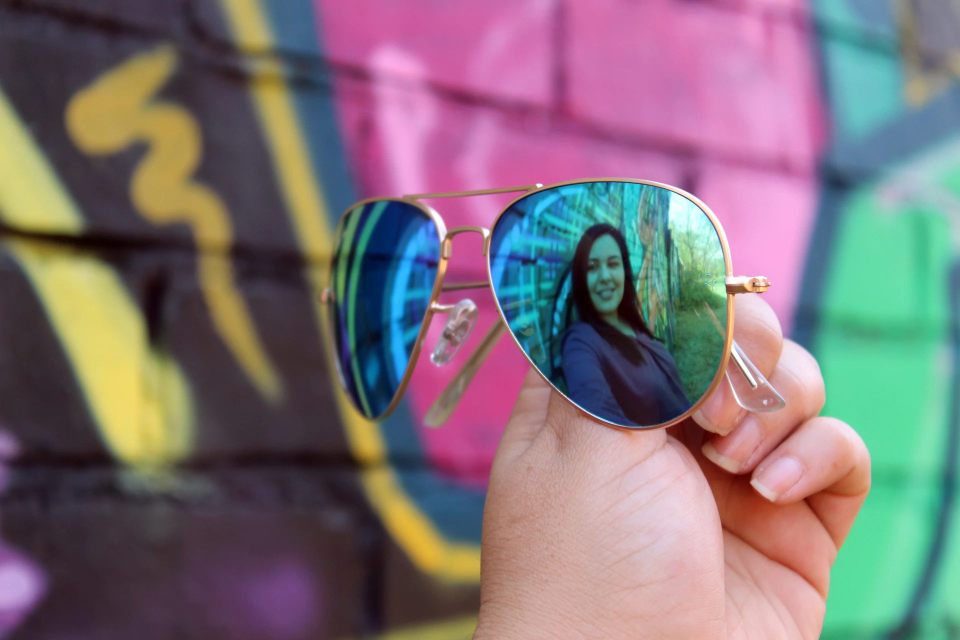 A vibrant outdoor scene featuring a model wearing trendy sunglasses, smiling against a bright blue sky backdrop.