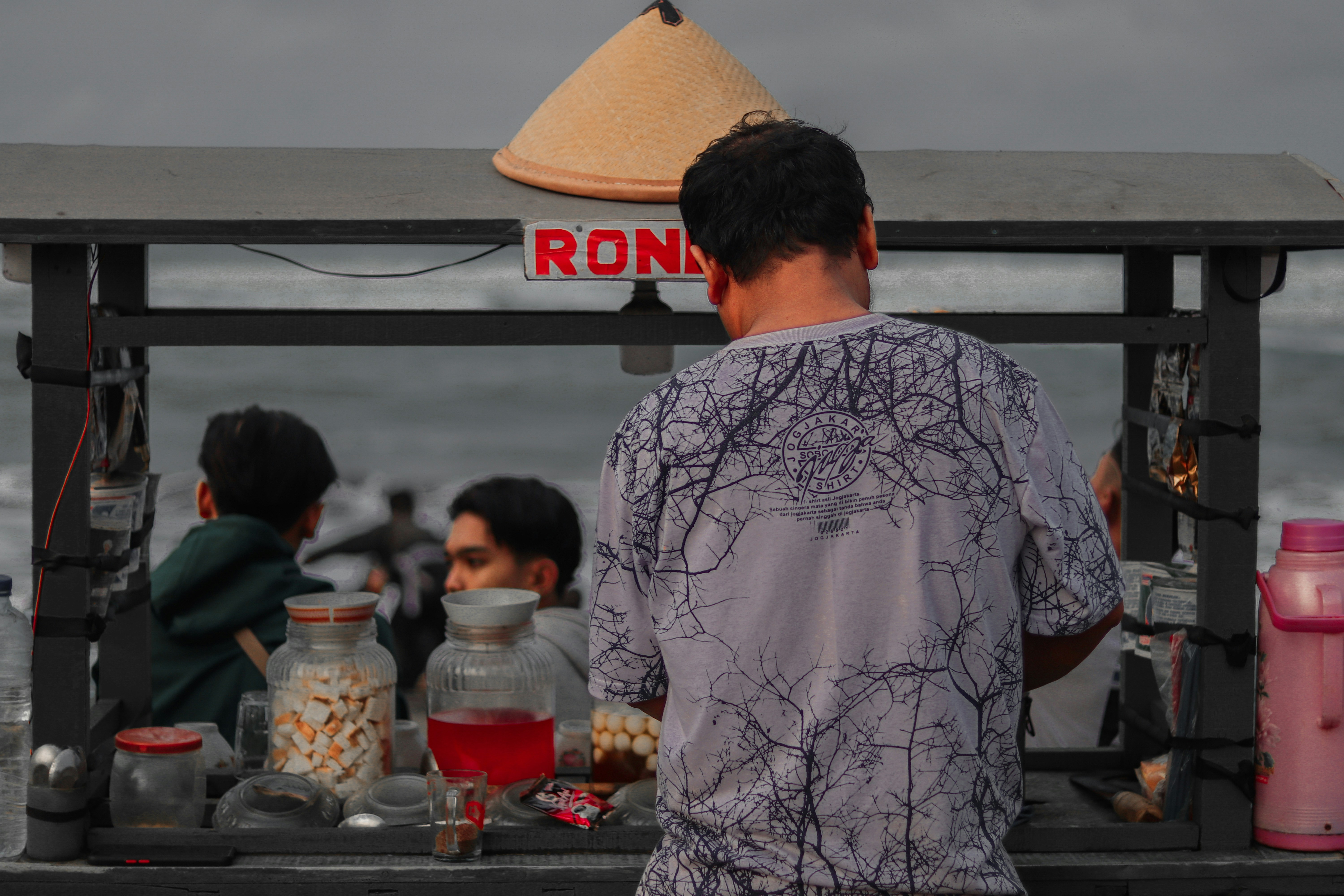 Seorang pria berdiri di depan kios makanan