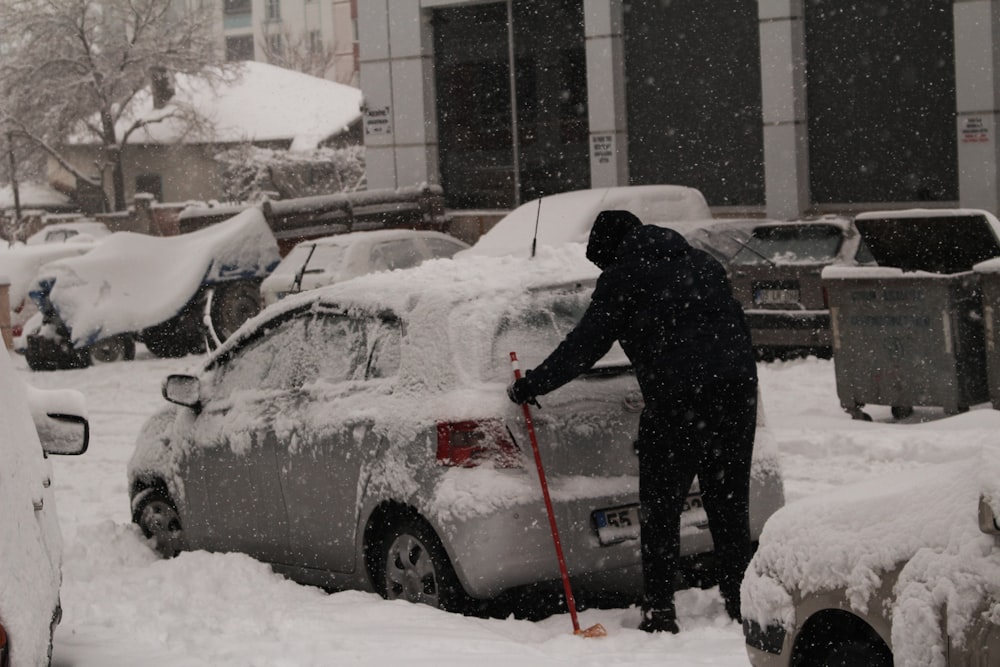 a person shoveling snow off a car