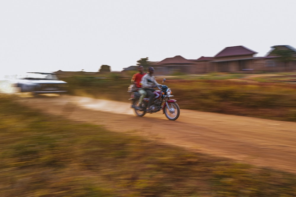 a couple of people riding a motorcycle on a dirt road