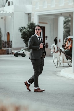 A man confidently walking in vibrant spring footwear on a sunny street.