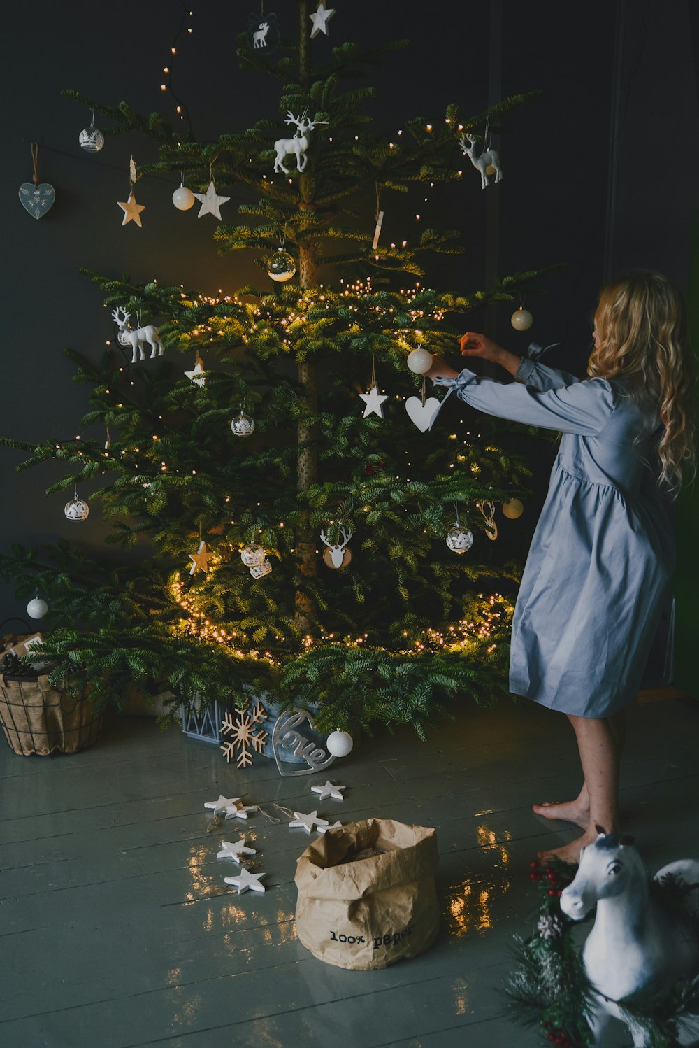 a man standing next to a tree with lights and ornaments