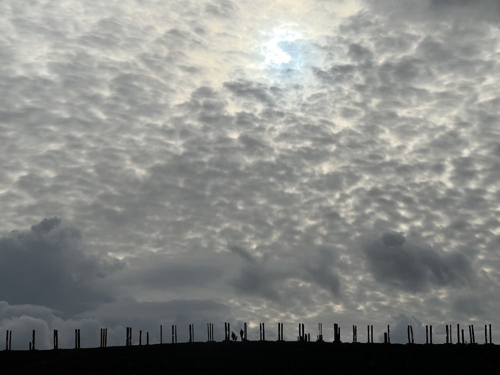 a cloudy sky with a row of wooden posts