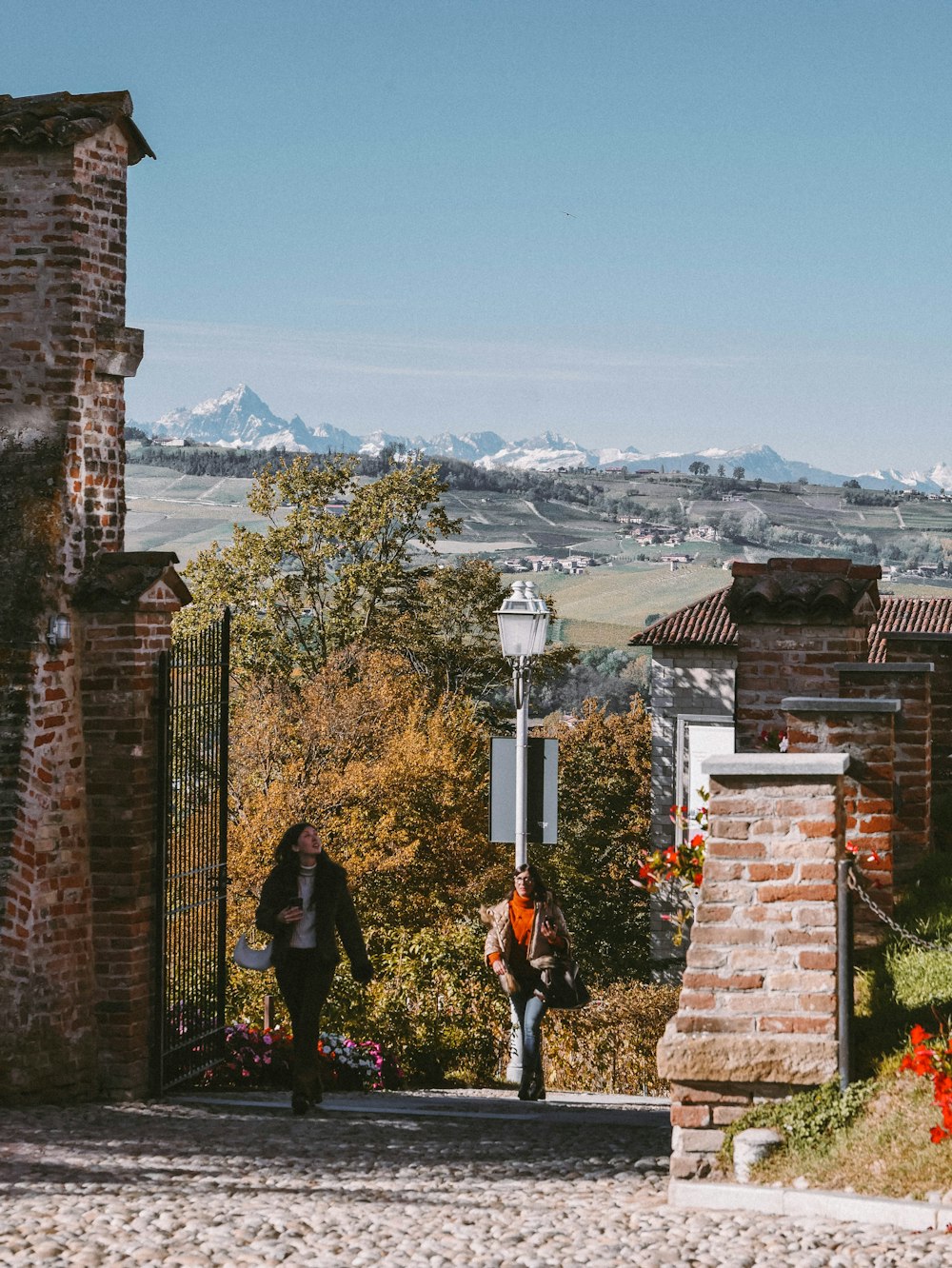 a couple of people standing on a stone wall overlooking a city