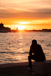 a person sitting on a bench looking at the water