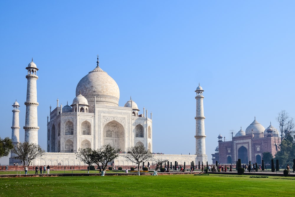 un gran edificio blanco con torres con el Taj Mahal al fondo