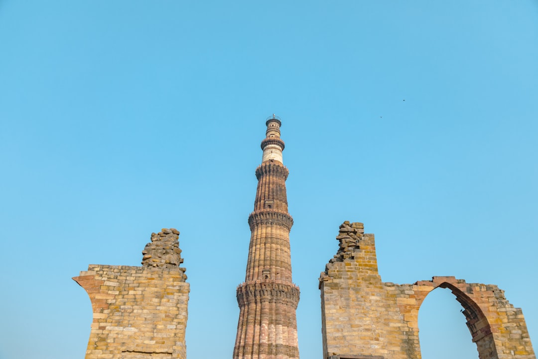 a group of tall towers with Qutub Minar in the background,