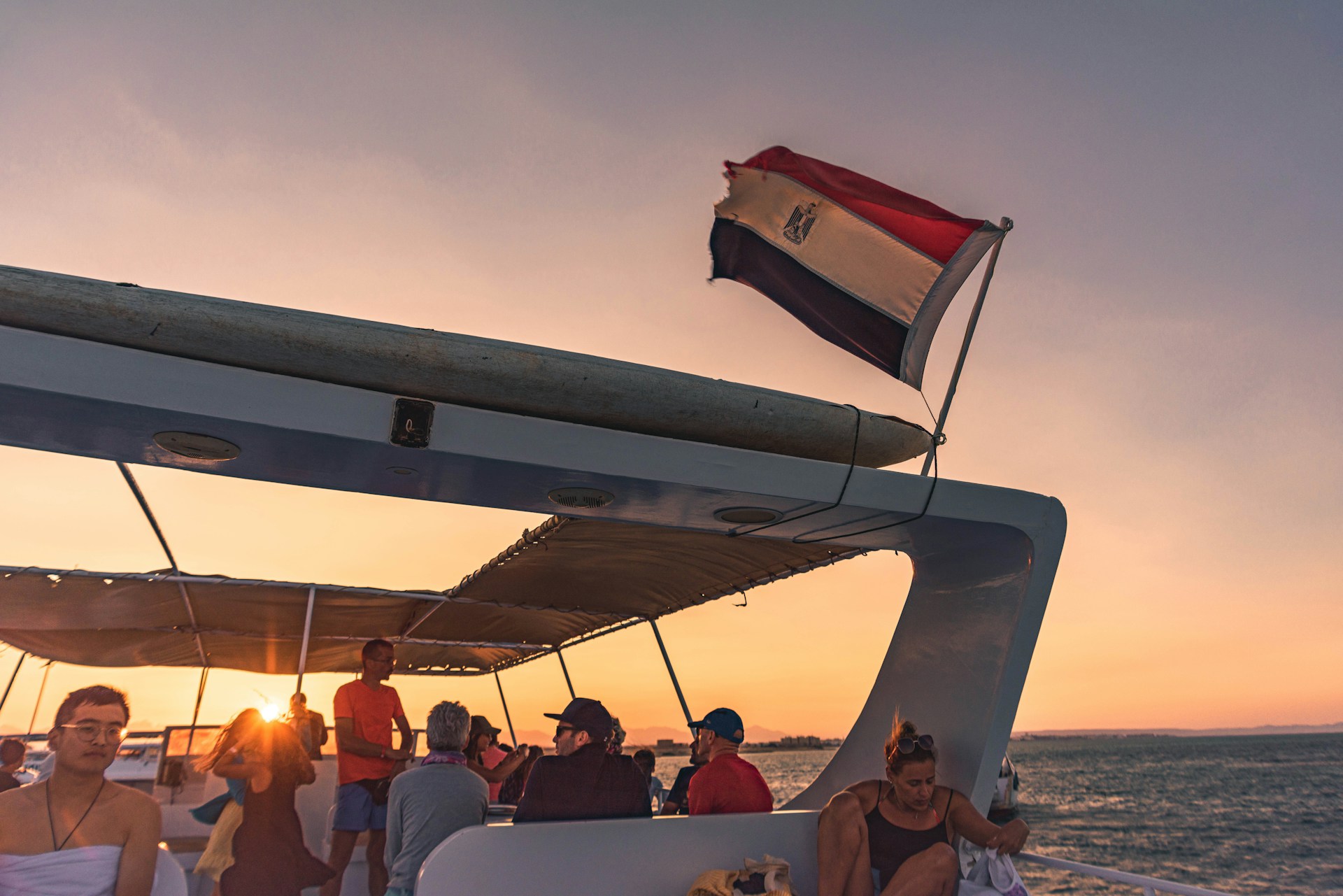 Guests relaxing on the deck of a sailboat, sipping drinks as the sun dips below the horizon.