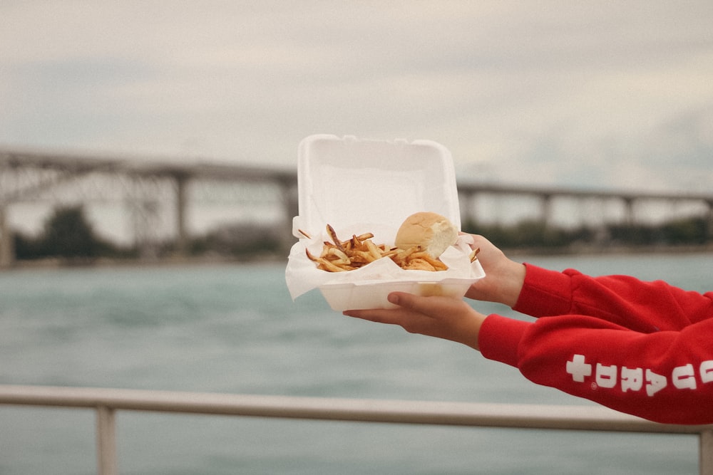 a hand holding a container of food