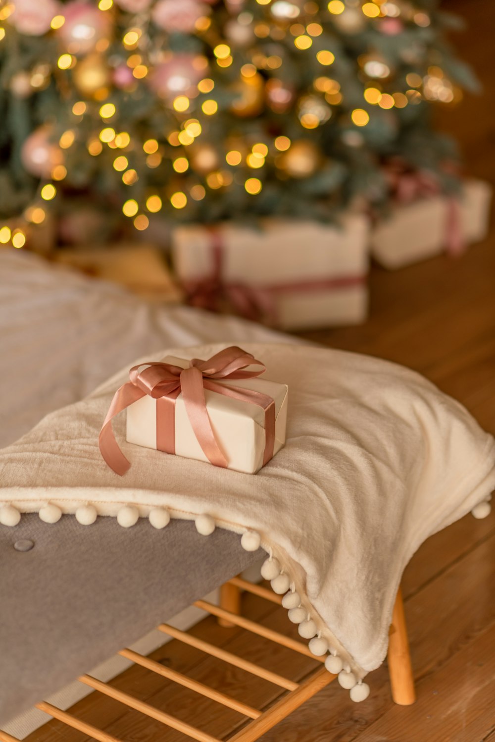 a white blanket with a pink bow on it in front of a christmas tree
