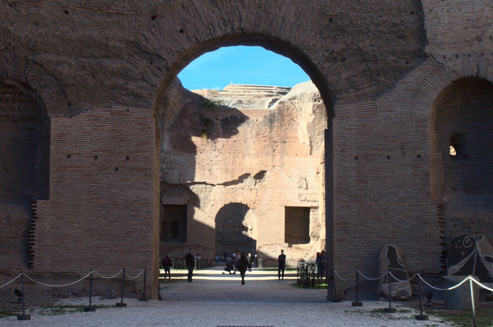 a group of people walking through a large brick archway
