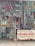 A cluttered workshop space filled with various car license plates, signs, and vintage posters. A red classic car painted on the wall has a pin-up model sitting on it. A ladder is placed in the middle of the space, surrounded by tools and mechanical parts. A banner in the foreground advertises auto and radiator repair services, listing contact numbers. The overall atmosphere suggests automotive workshop or restoration.