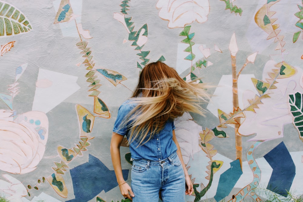 a woman looking at a wall with art