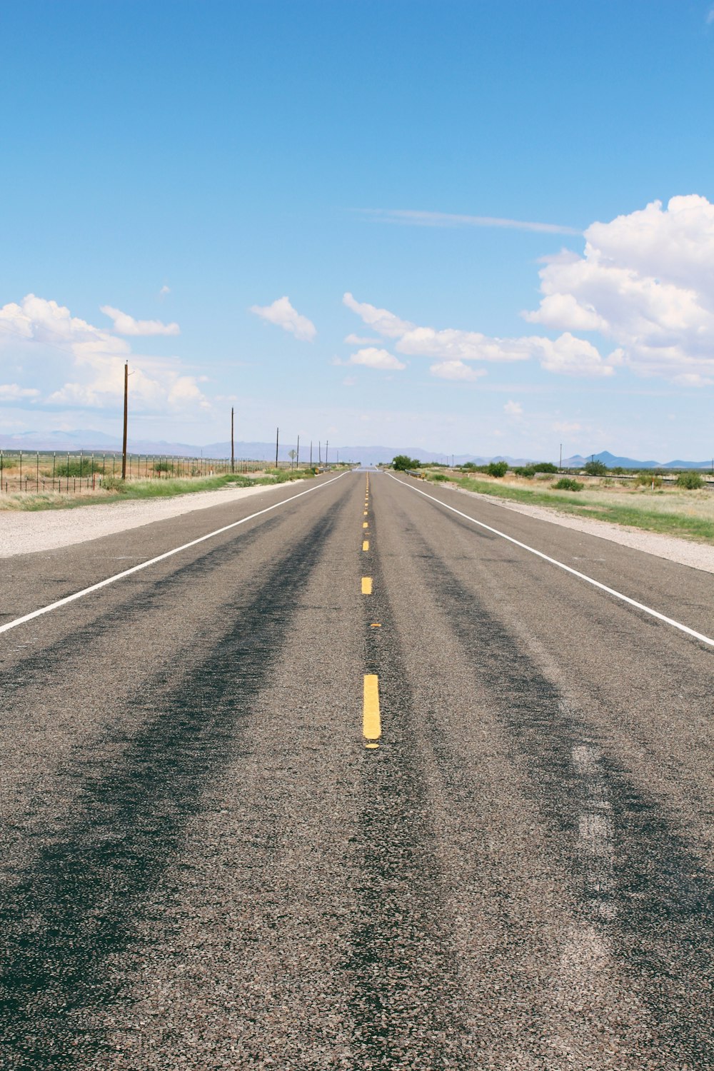 a road with a yellow line with Nullarbor Plain in the background