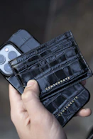 a hand holding a black wallet