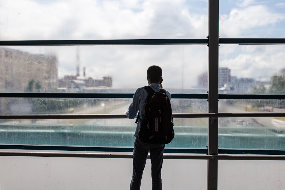 a man standing in front of a window looking out at a city