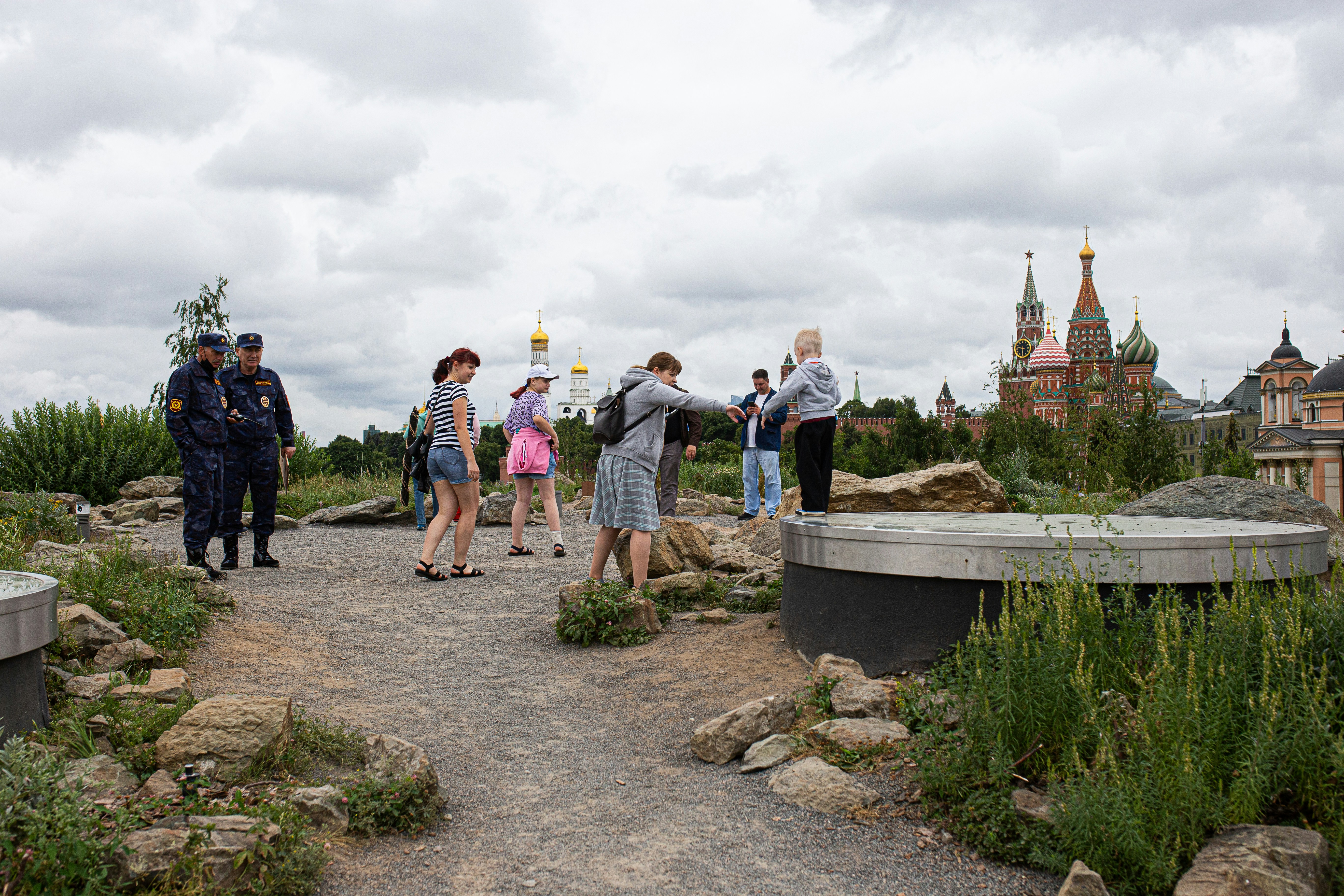a group of people standing on a rocky hill with a bridge and buildings in the background