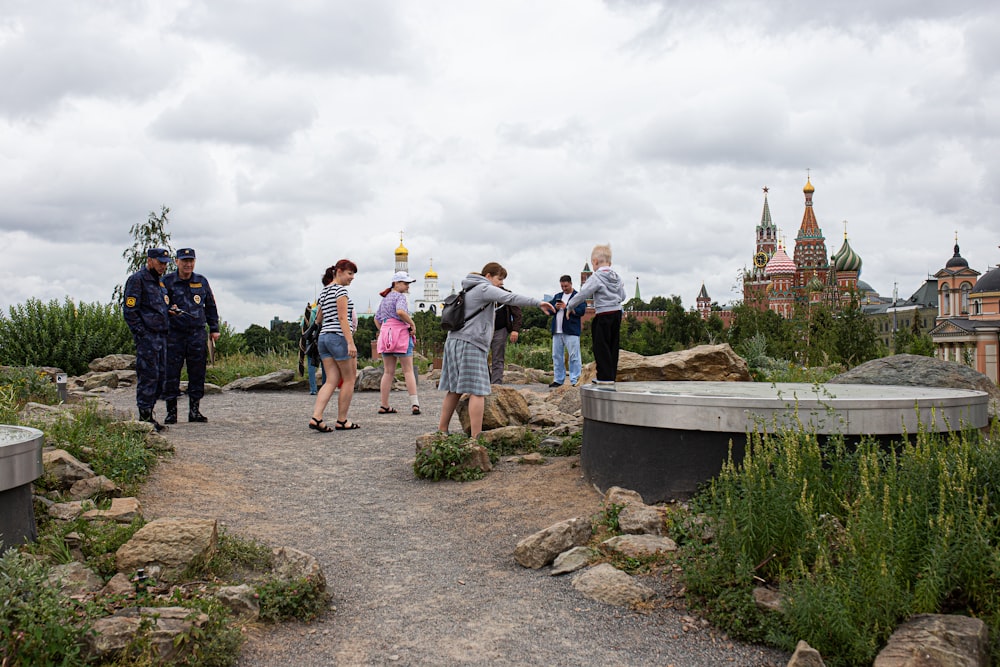 a group of people standing on a rocky hill with a bridge and buildings in the background