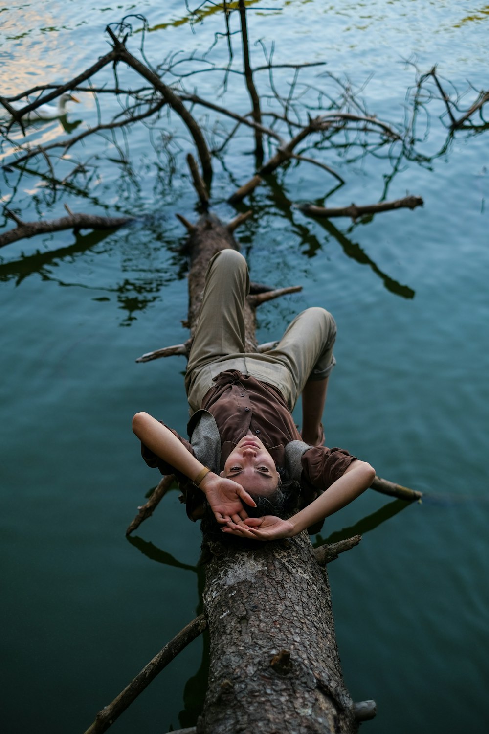 a man and woman lying on a tree branch in the water