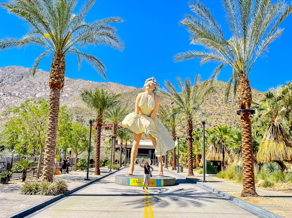 a statue of a person in a dress surrounded by palm trees