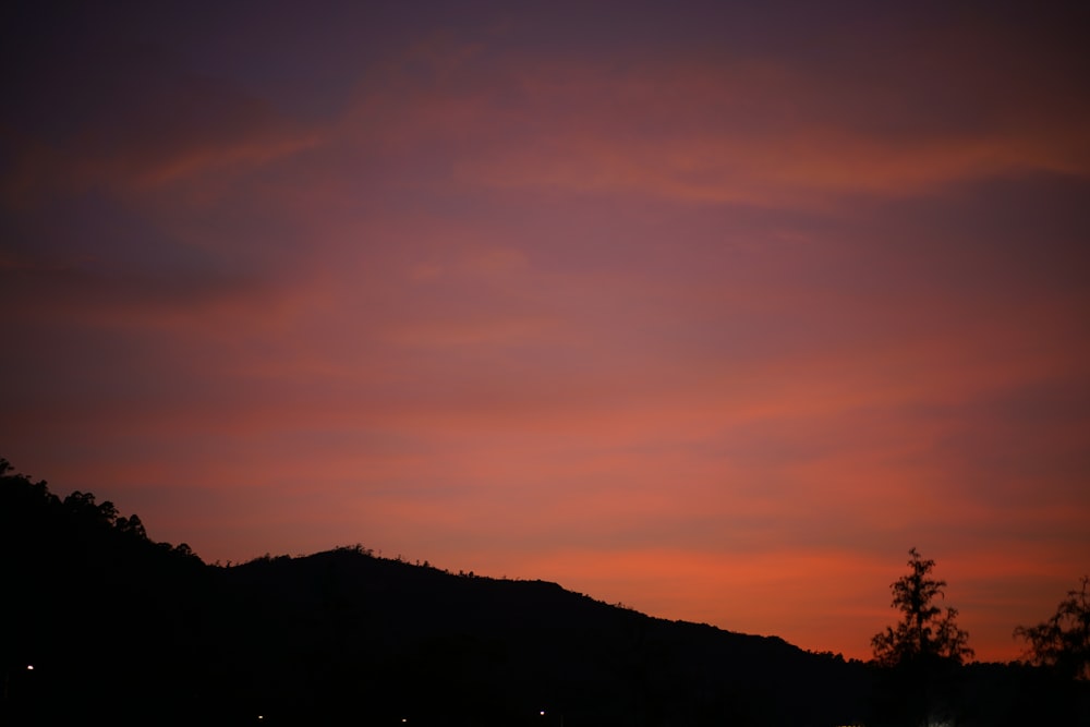 a pink and purple sky over a hill