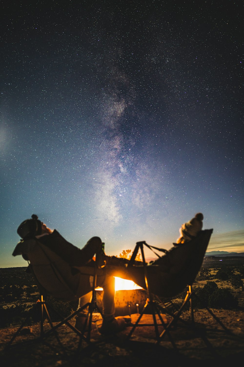 a group of people sitting around a campfire at night